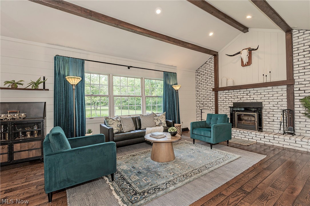 11292 Butternut Road Chardon, OH 44024 - Photo 10 of 49 Vaulted ceiling living room featuring a white brick fireplace, exposed wood beams, shiplap wall accents, and wood-finish flooring