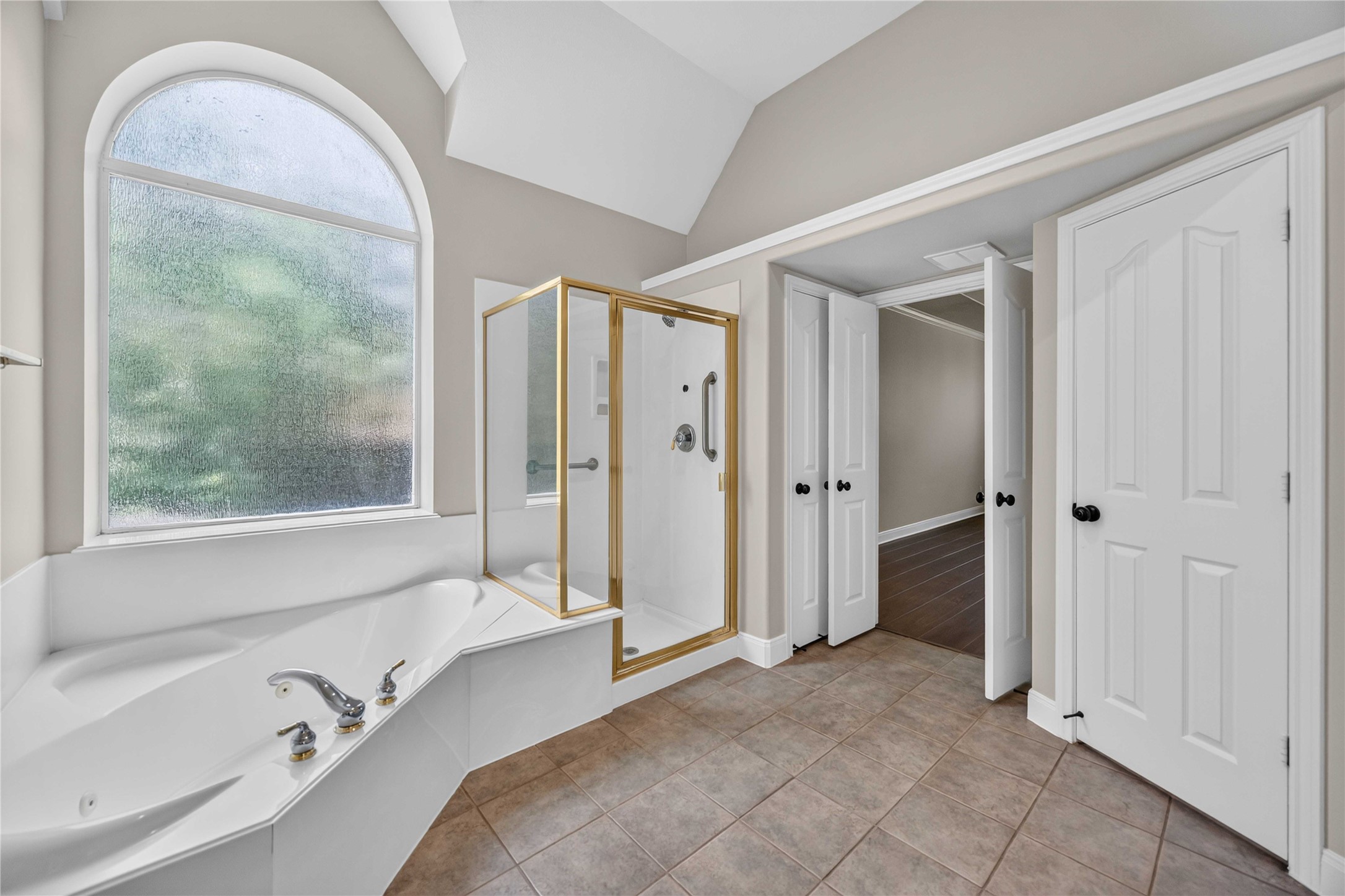 3303 Raleigh Row Missouri City, TX 77459 - Photo 29 of 50 Spacious Primary bathroom featuring a luxurious corner bathtub, separate glass-enclosed shower with gold trim, and large frosted window for natural light.