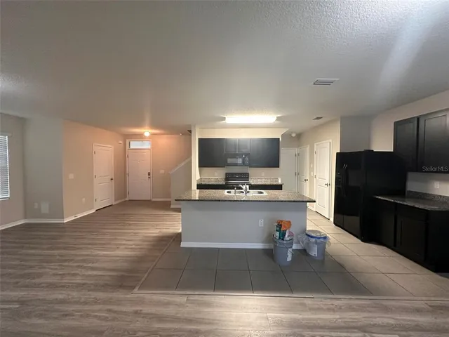 a living room with stainless steel appliances kitchen island granite countertop a refrigerator stove and oven