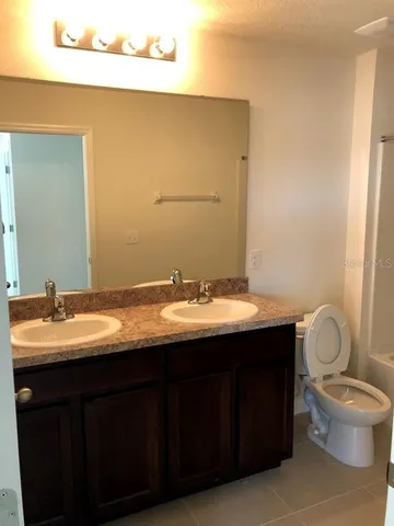 a bathroom with a granite countertop sink toilet and mirror