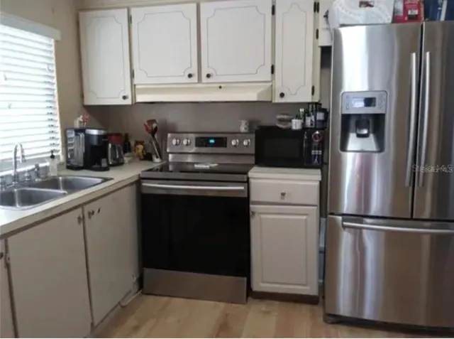 a kitchen with appliances a refrigerator and cabinets