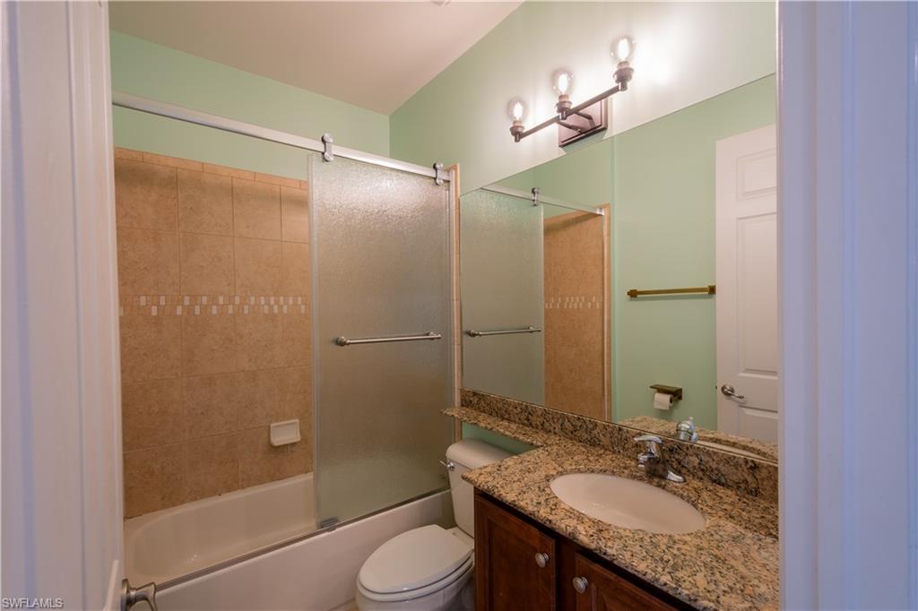 6533 Monterey Point, Unit 204 Naples, FL 34105 - Photo 22 of 41 a bathroom with a granite countertop sink toilet mirror and shower