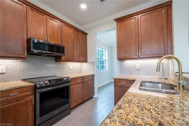 a kitchen with granite countertop wooden cabinets stainless steel appliances and a sink