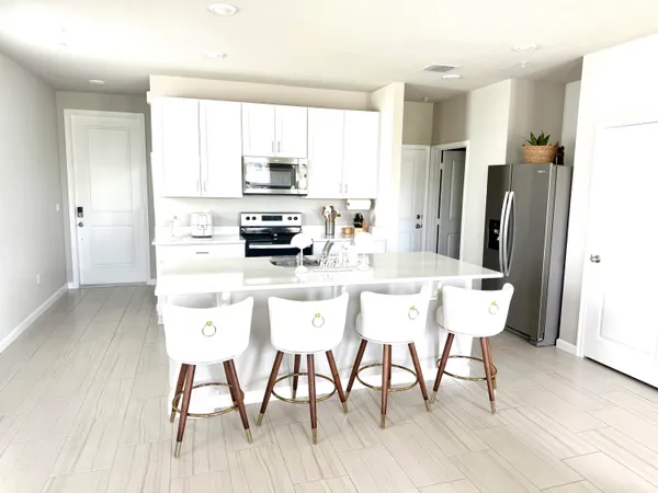 a kitchen with stainless steel appliances a table chairs refrigerator and sink