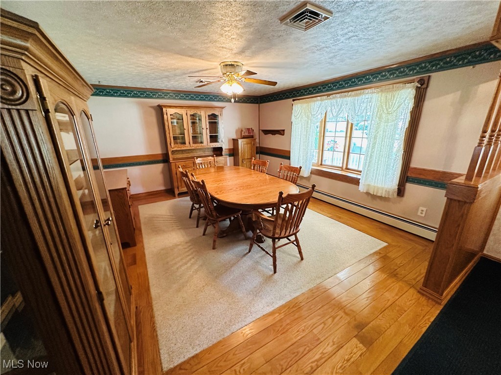 1684 Morris Street Mineral Ridge, OH 44440 - Photo 23 of 50 Dining area with baseboard heating, a textured ceiling, light wood finished floors, ceiling fan, and crown molding