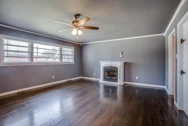 an empty room with wooden floor fireplace and windows