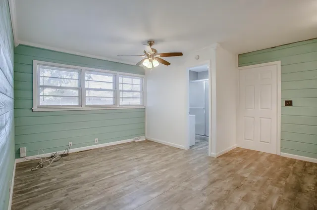 a view of empty room with wooden floor and fan