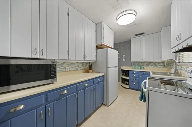 a kitchen with stainless steel appliances granite countertop a refrigerator a stove a sink and white cabinets
