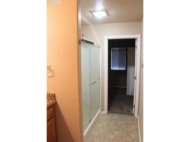a view of a hallway with wooden floor and a bathroom view