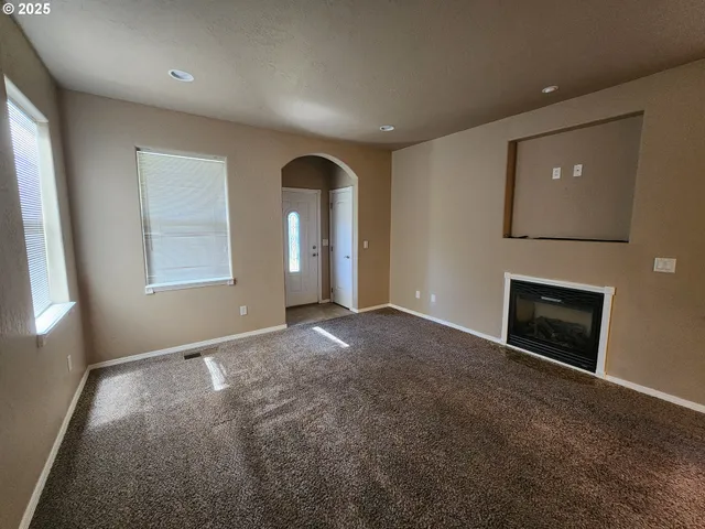 an empty room with windows and fireplace