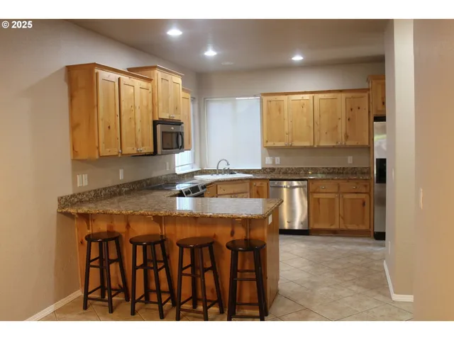 a kitchen with stainless steel appliances granite countertop a stove a sink and a microwave