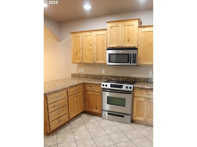 a kitchen with stainless steel appliances granite countertop a stove top oven microwave and view living room