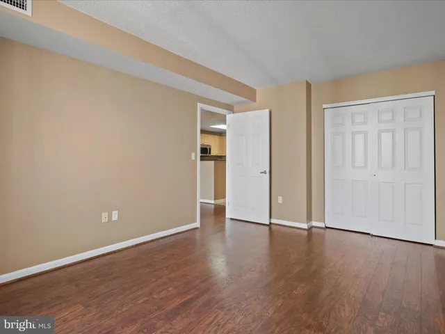 a view of an empty room with wooden floor and closet