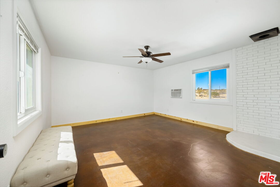 57157 Emerald Way Landers, CA 92285 - Photo 7 of 12 a view of a big room with wooden floor a ceiling fan and windows