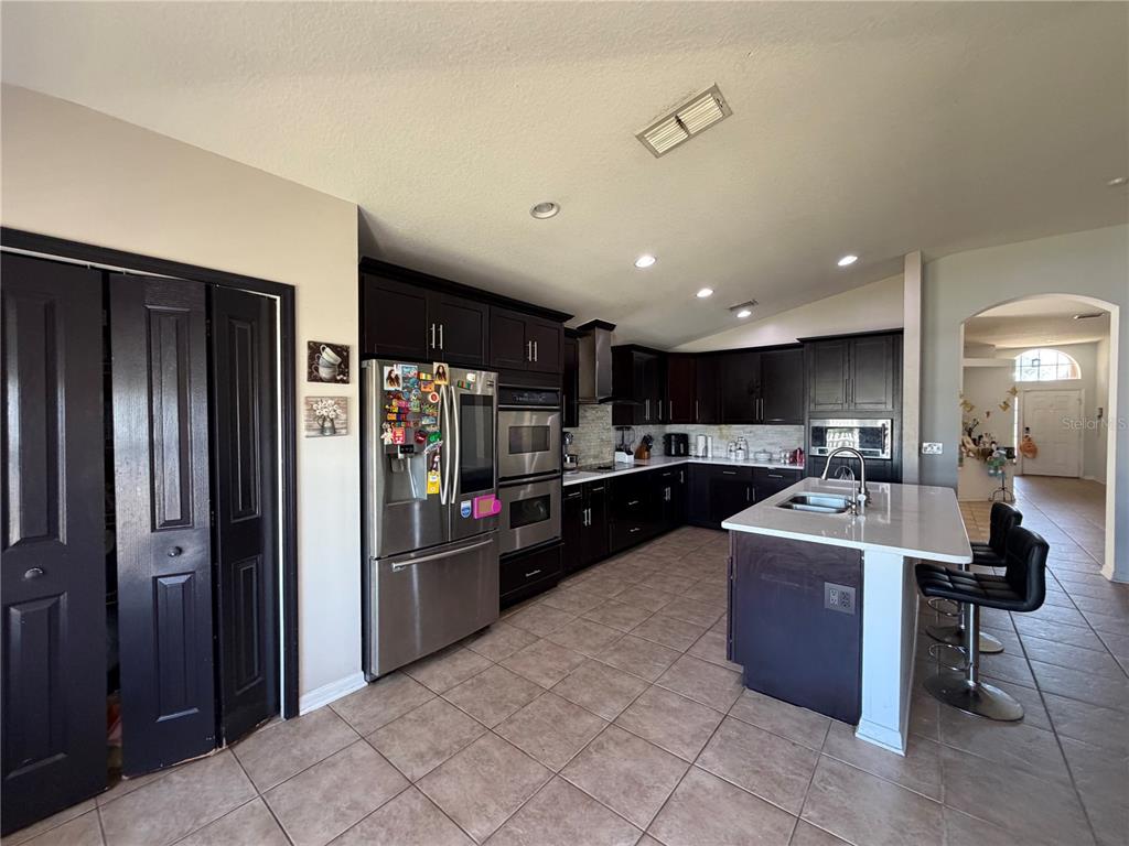 945 Tramells Trail Kissimmee, FL 34744 - Photo 13 of 36 a kitchen with stainless steel appliances kitchen island granite countertop a refrigerator and a sink