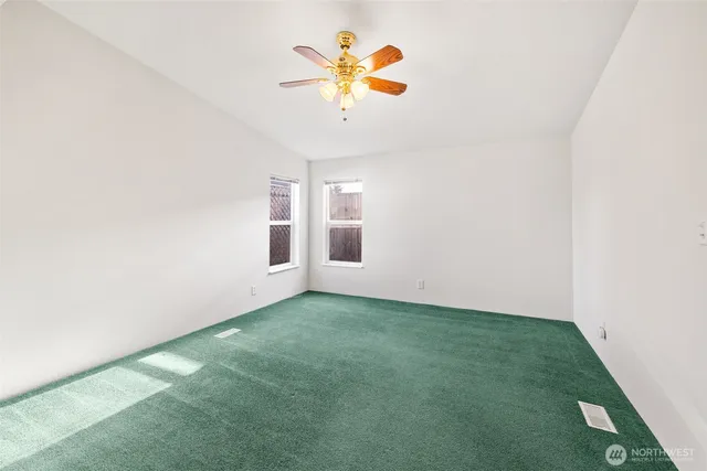 a view of a room with a ceiling fan and carpet