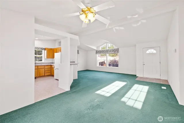 an empty room with chandelier fan and windows
