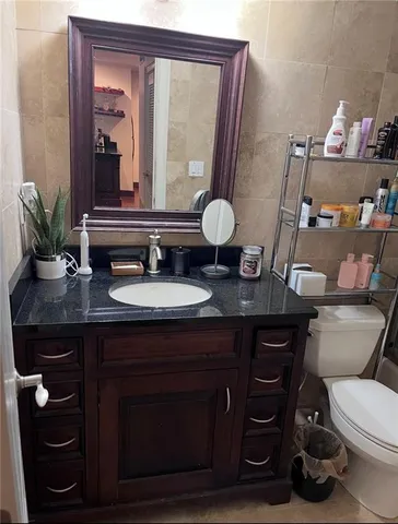 a bathroom with a granite countertop sink a toilet and a mirror