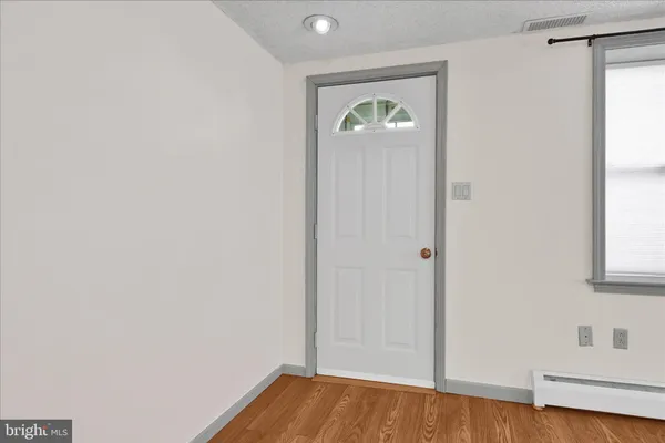 a view of hallway with window and wooden floor