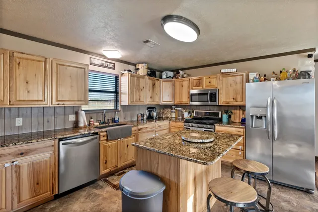 a kitchen with stainless steel appliances granite countertop a sink stove refrigerator and cabinets