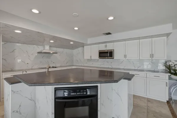 a kitchen with stainless steel appliances granite countertop a sink a stove and a microwave