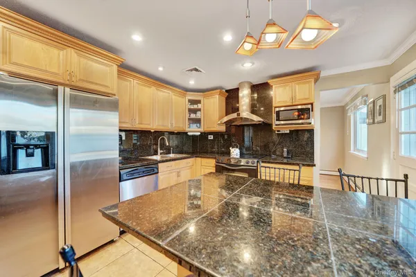 a kitchen with stainless steel appliances granite countertop a refrigerator a oven a sink a dining table and chairs with wooden floor