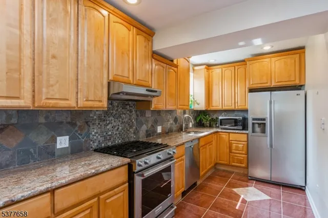 a kitchen with stainless steel appliances granite countertop a stove a refrigerator and a sink