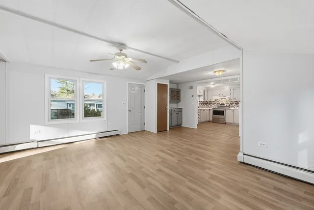 an empty room with wooden floor and a kitchen