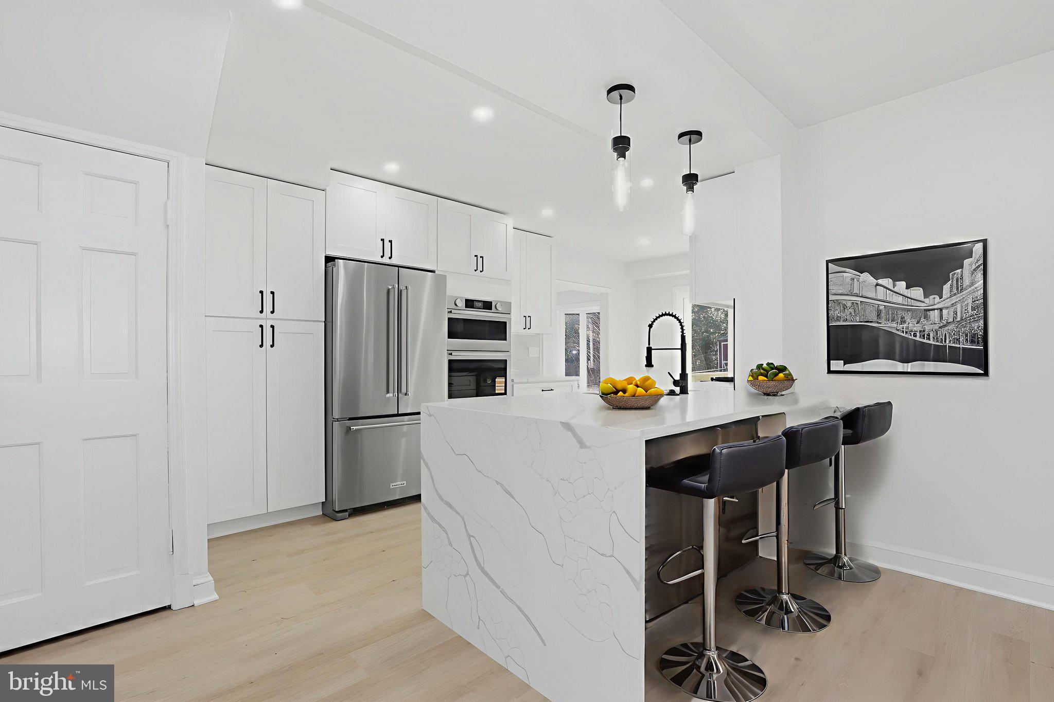 a kitchen with stainless steel appliances a refrigerator a sink a stove a dining table and chairs