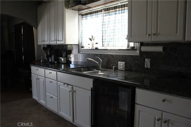 a kitchen with stainless steel appliances granite countertop a sink window and cabinets