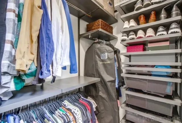 a view of walk in closet with clothes and shoes
