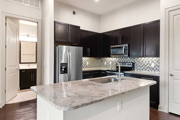a kitchen with kitchen island a counter top space cabinets and stainless steel appliances