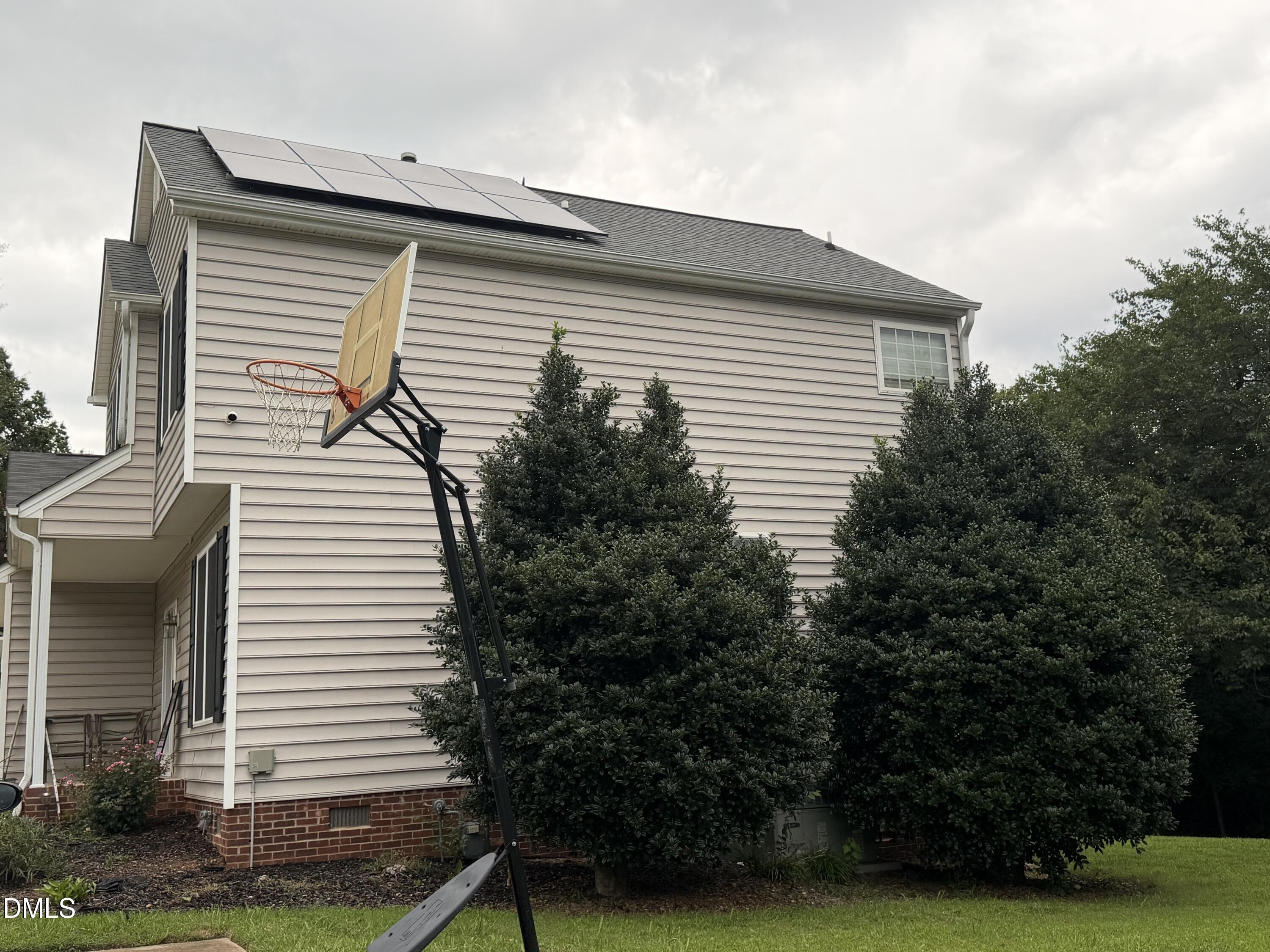 1849 Hanford Hills Road Graham, NC 27253 - Photo 3 of 11 Solar panel array, neutral-toned siding, grey shingle roof, mature landscaping, and brick foundation