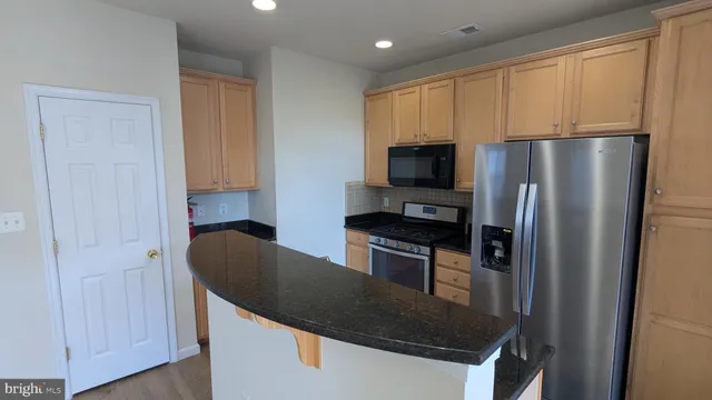 a kitchen with stainless steel appliances granite countertop a refrigerator a sink and a stove