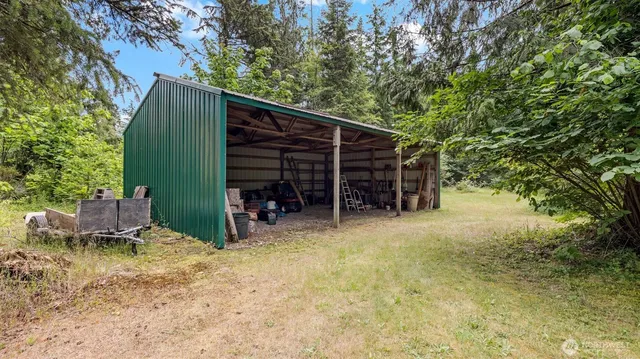 an aerial view of residential house with outdoor space and trees all around