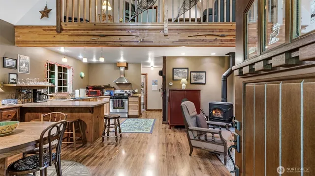 a kitchen with stainless steel appliances granite countertop a refrigerator a stove a sink and chairs with wooden floor