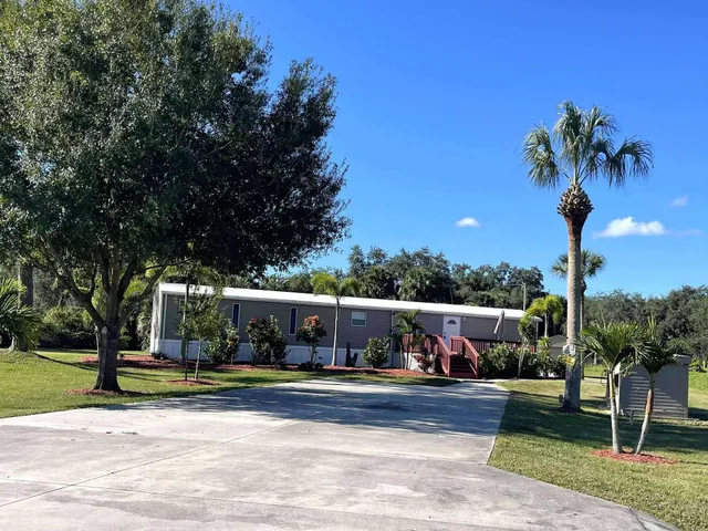 a view of a house with a yard and palm trees