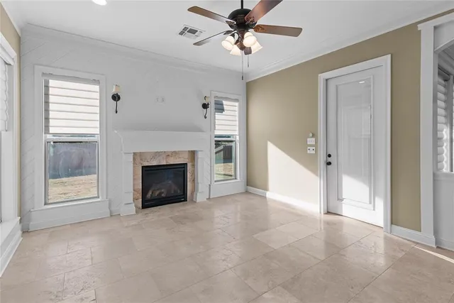 a view of a livingroom with a fireplace a ceiling fan and windows
