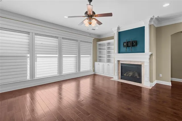 a view of an empty room with wooden floor fireplace and a window