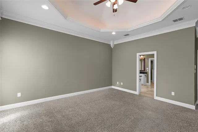an empty room with a chandelier fan and windows