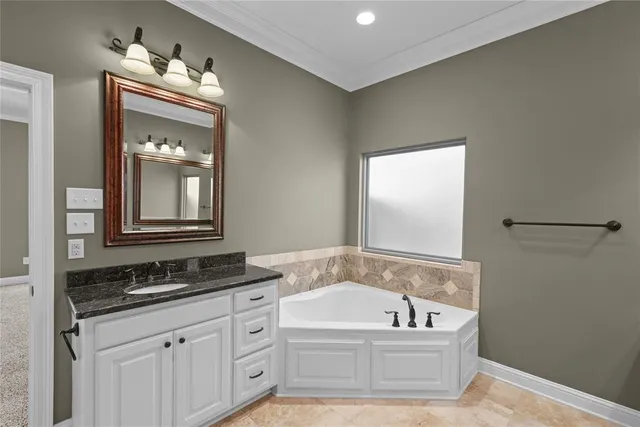 a bathroom with a granite countertop tub sink and mirror