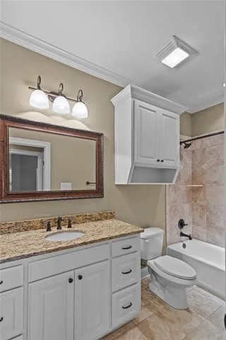 a bathroom with a granite countertop toilet sink and mirror