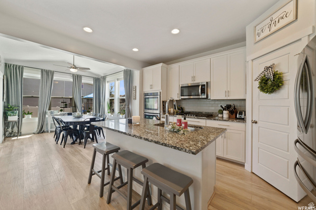 1836 Red Oak Road Eagle Mountain, UT 84005 - Photo 10 of 15 Kitchen featuring a breakfast bar area, light wood-style floors, stainless steel appliances, dark stone countertops, and recessed lighting