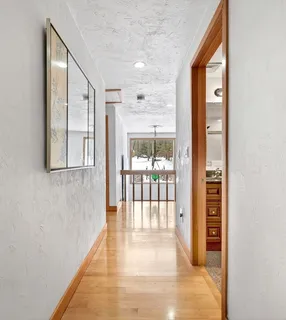 a view of a hallway with wooden floor and windows