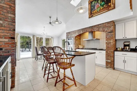 a kitchen with stainless steel appliances granite countertop a stove a sink a dining table and chairs with wooden floor