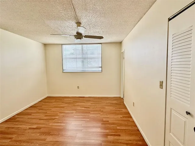 an empty room with wooden floor and a ceiling fan