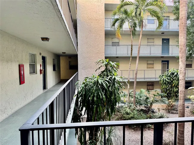 a view of a hallway with wooden floor and a bathroom