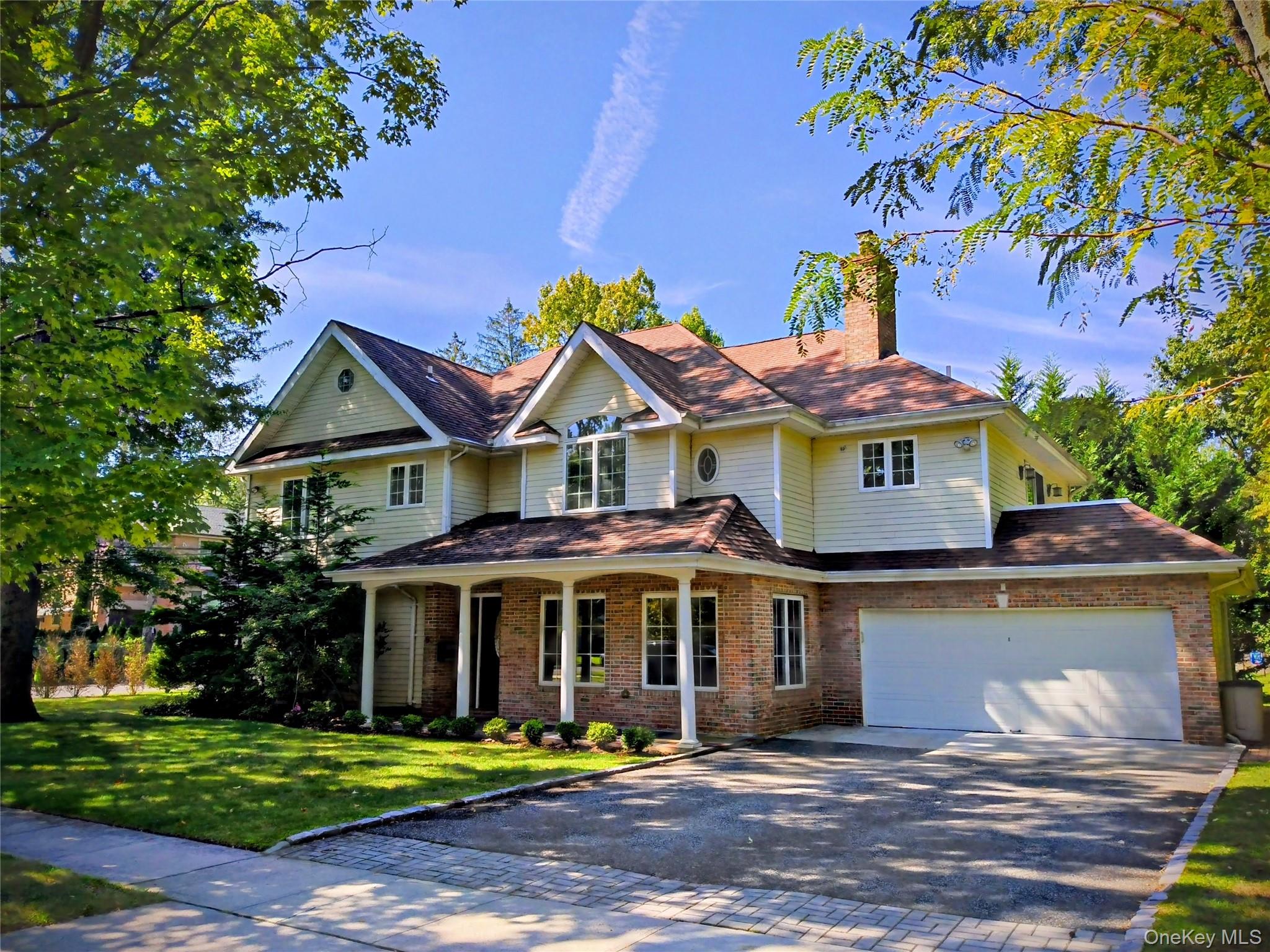 View of front of home featuring a porch, driveway, brick siding, and a garage