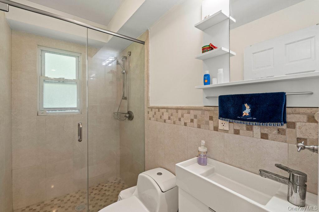 60 Plymouth Road Great Neck, NY 11023 - Photo 15 of 36 Bathroom with a shower stall, tile walls, and vanity