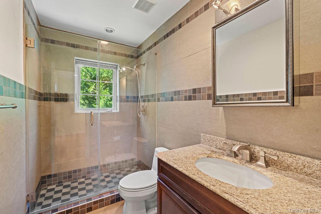 60 Plymouth Road Great Neck, NY 11023 - Photo 23 of 36 Full bathroom featuring vanity, a stall shower, and tile walls